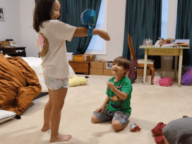 kids playing with a suspended, laundry-grabbing robot head