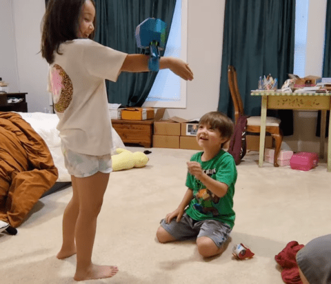 kids playing with a suspended, laundry-grabbing robot head